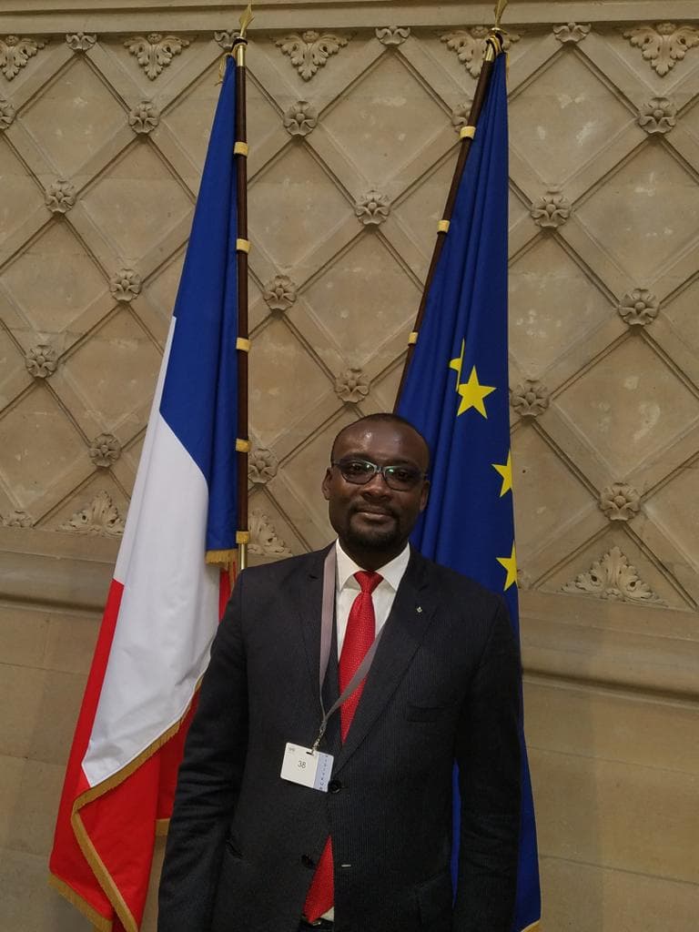 Maître Luku Clément devant les drapeaux français et européen